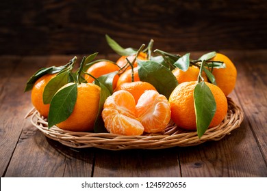 Fresh mandarin oranges fruit or tangerines with leaves on wooden table