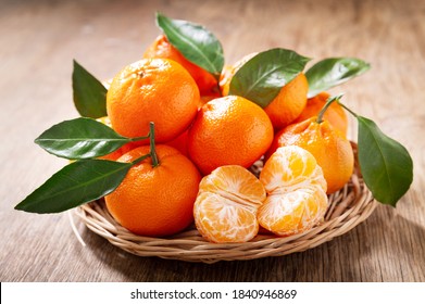 Свежие мандарины, апельсины, фрукты или мандарины с листьями на деревянном столе