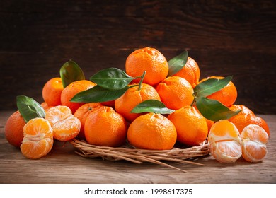 Fresh mandarin oranges fruit or tangerines with leaves on a wooden background