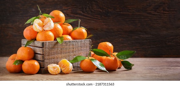 Mandarinas frescas naranjas o mandarinas con hojas en una caja sobre fondo de madera