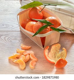 Fresh Mandarins Fruits With Leaves On Wooden Table In Wooden Punett ,one Fruit Has Been Peeled