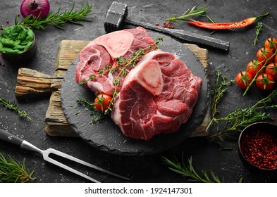 Fresh meat. Ossobuko steak on the bone with rosemary and spices. On a black stone background. Top view.