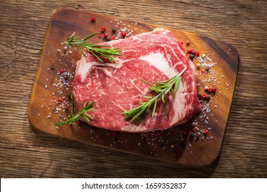 fresh meat with rosemary and spices on a wooden board, top view - Shutterstock ID 1659352837