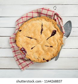 Fresh And Messy Baked Blackberry Pie With Red Plaid Towel And Server On White Shiplap Board Background Table With Square Crop And Above, Looking-down View.  Some Room On Sides For Copy, Text Or Words