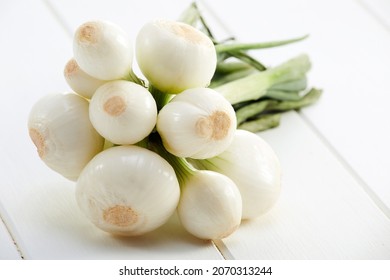 Fresh Mexican spring onions or chambray onions over a white wooden table.