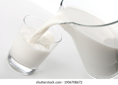 Le lait frais contenu dans une carafe est versé dans un verre. Le calcium est bon pour la santé. Photo isolée sur fond blanc