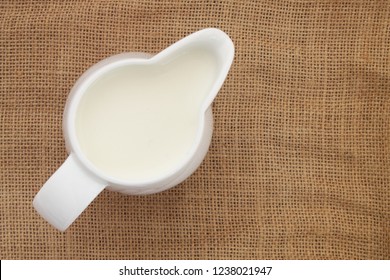 Fresh Milk In Jug On Rustic Burlap Background, Top View