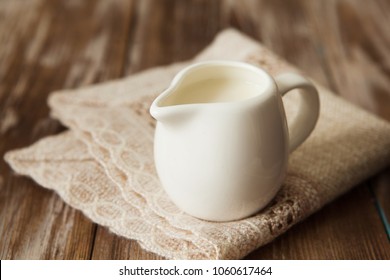 Fresh milk in jug on the wooden table for breakfast copy space