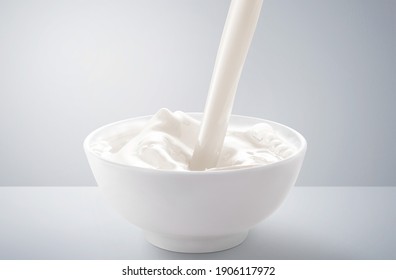 Fresh milk pouring in bowl with splash. isolated on grey and white background.