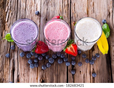 Fresh milk, strawberry, blueberry and banana drinks on wodeen table, assorted protein cocktails with fresh fruits. 