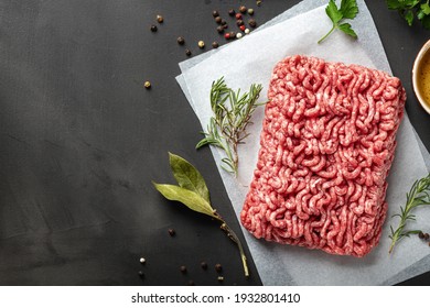 Frisches Hackfleisch auf dunklem Hintergrund, mit Zutaten zum Kochen von Draufsicht