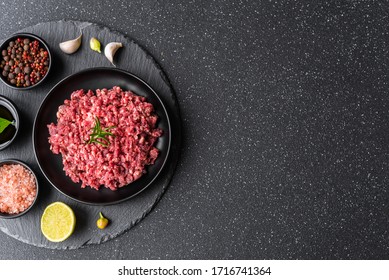 Fresh minced meat ground beef on a black plate against stone background
