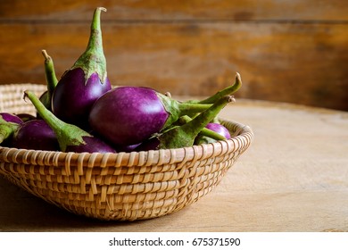 Fresh Mini Purple Eggplant In Basket On Wooden Background. Eggplant Has Benefits To Help Build Strong Bones, Prevent Osteoporosis And Cancer, Help Lose Weight And Manage Diabetes.