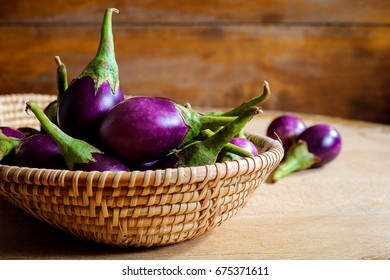 Fresh Mini Purple Eggplant In Basket On Wooden Background. Eggplant Has Benefits To Help Build Strong Bones, Prevent Osteoporosis And Cancer, Help Lose Weight And Manage Diabetes.