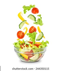 Fresh Mixed Vegetables Falling Into A Bowl Of Salad. Isolated On White.
