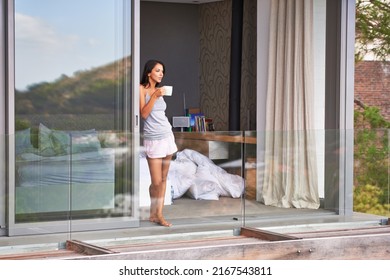 Fresh morning air and coffee. Shot of an attractive woman enjoying the fresh air and coffee on her balcony. - Powered by Shutterstock