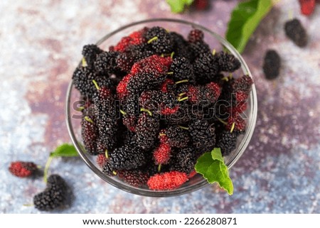 fresh mulberry fruit with green mulberry leave in a glass bowl.