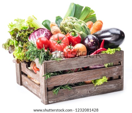 Fresh multi-colored vegetables in wooden crate. White background.