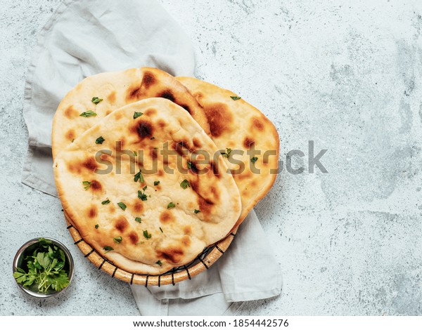 Fresh naan bread on gray\
cement background with copy space. Top view of several perfect naan\
flatbreads