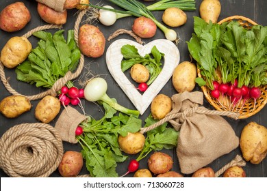 Fresh natural vegetables. Carrots, potatoes and radishes on a black wooden background. Rustic style.
