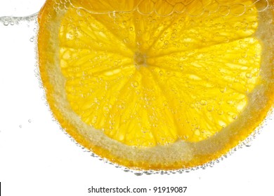 A Fresh Naval Orange Slice Floats In Carbonated Water, Backlit On White