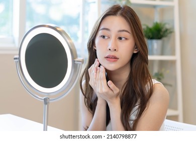 Fresh, nice healthy skin, beautiful of asian young woman, girl looking at mirror, touching her face with before make up cosmetic routine at home. Female look with natural fashion style, Facial Beauty.