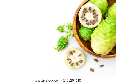 Fresh noni fruit or morinda citrifolia (  indian mulberry, cheese fruit ) and slices in wood bowl isolated on white background. Copyspace for text and content. Top view.
