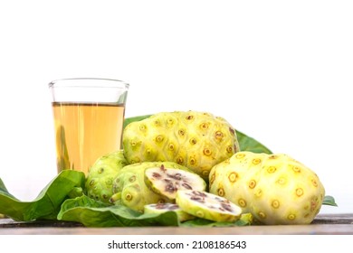 Fresh Noni Fruit Or Morinda Citrifolia On Leaf And Noni Drink For Health On Wooden Table And White Background.