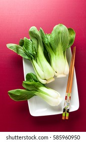 Fresh Not Cooked Bok Choy On Cerise Background. Chinese Chopsticks. Asian Cuisines Ingredient