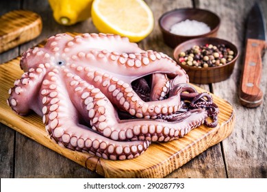 fresh octopus in the bowl with lemon, sea salt and pepper on wooden rustic table