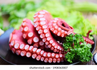 Fresh octopus food on black plate, cooked squid salad vegetable seafood cuttlefish dinner restaurant, Boiled octopus tentacles