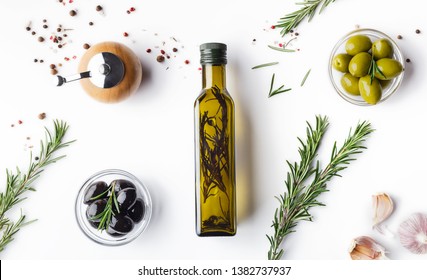 Fresh olives and oil in bottle with rosemary on white background with scattered spicies, top view