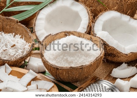 Fresh opened coconuts along with coconut slices, flakes and coconut leaves on a wooden table. Nice fruit background for your projects. 