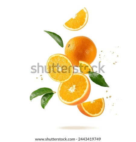 Fresh orange fruit whole and slices with drops and leaves falling flying isolated on white background