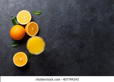 Fresh Orange Fruits And Juice On Stone Table. Top View With Copy Space