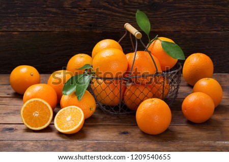 fresh orange fruits with leaves in a basket on wooden table