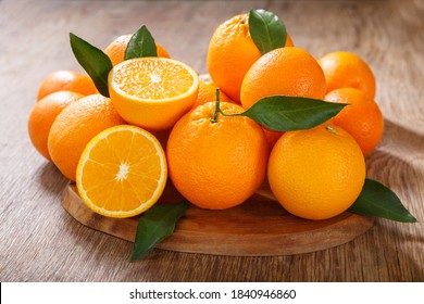 fresh orange fruits with leaves on a wooden table