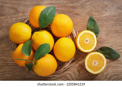 fresh orange fruits with leaves on a wooden background, top view