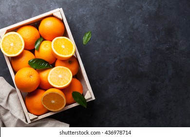 Fresh Orange Fruits In Wooden Box On Stone Table. Top View With Copy Space