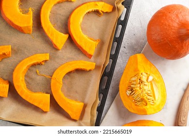 Fresh Orange Hokkaido Pumpkin Cut In Half On White Marble Cutting Board, Slices Of Pumpkin On Baking Paper