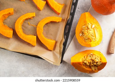 Fresh Orange Hokkaido Pumpkin Cut In Half On White Marble Cutting Board, Slices Of Pumpkin On Baking Paper