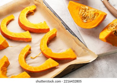 Fresh Orange Hokkaido Pumpkin Cut In Half On White Marble Cutting Board, Slices Of Pumpkin On Baking Paper