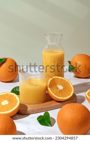 fresh orange juice in a glass and decanter. Oranges on the table