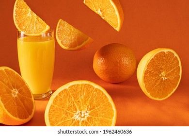 Fresh Orange Juice In Glass And  Falling  Orange Slices.Orange Background.Monochromatic Food Photography.