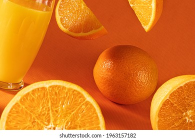 Fresh Orange Juice In Glass And  Falling  Orange Slices.Orange Background.Monochromatic Food Photography.