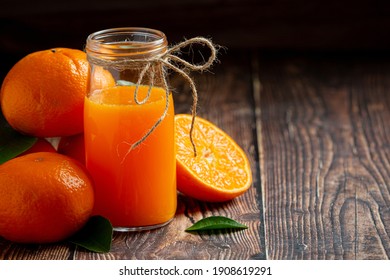 Fresh orange juice in the glass on dark wooden background