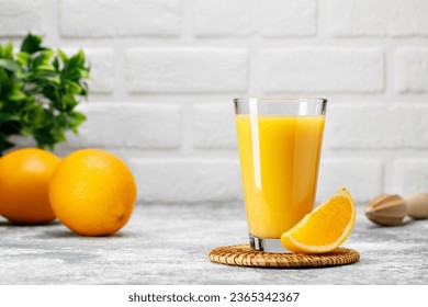 fresh orange juice in glass with slice of fruit on table with white brick wall as background - Powered by Shutterstock