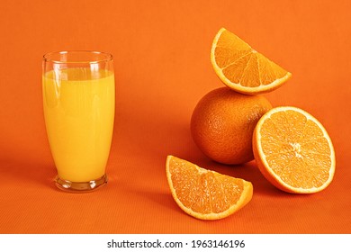 Fresh Orange Juice In Glass And Orange Slices.Orange Background.Monochromatic Food Photography.