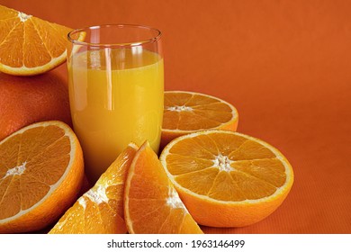 Fresh Orange Juice In Glass And Orange Slices.Orange Background.Monochromatic Food Photography.Copy Space.