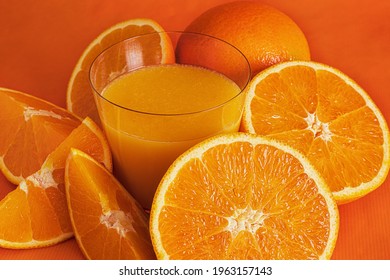 Fresh Orange Juice In Glass And Orange Slices.Orange Background.Monochromatic Food Photography.